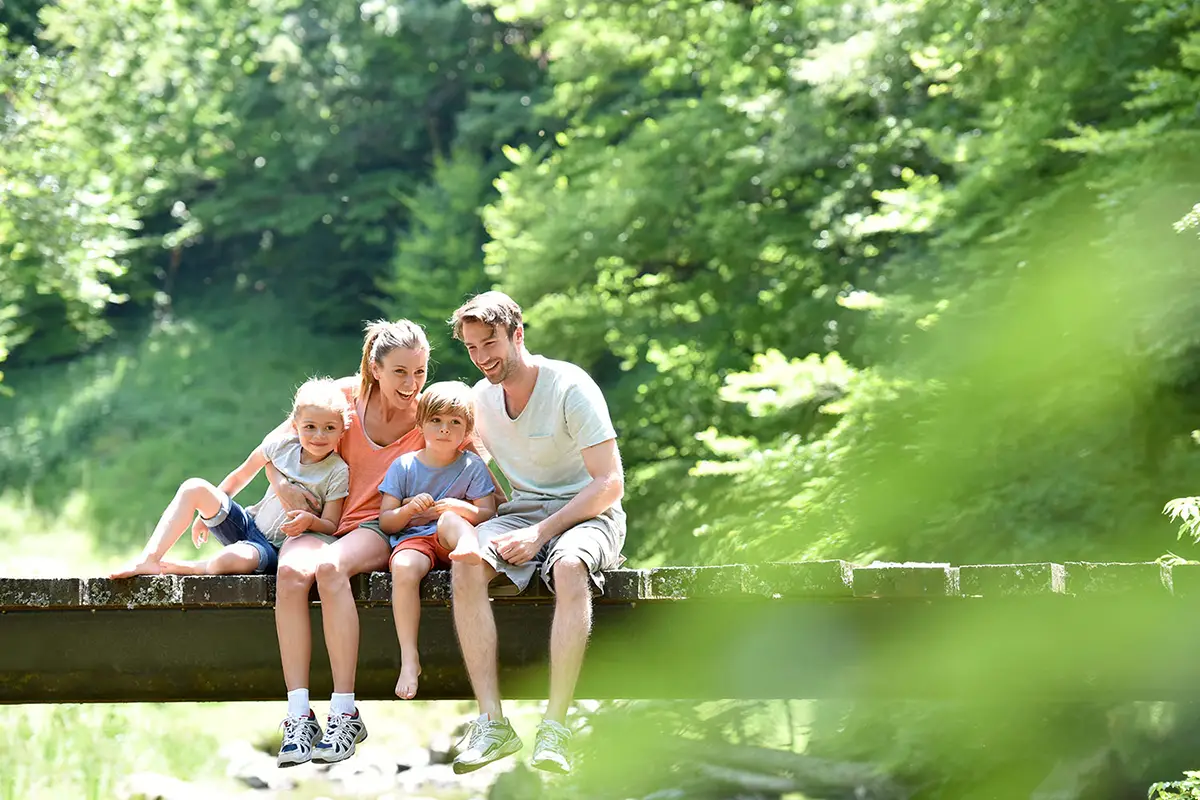 famiglia seduta su un tronco mentre osserva gli alberi