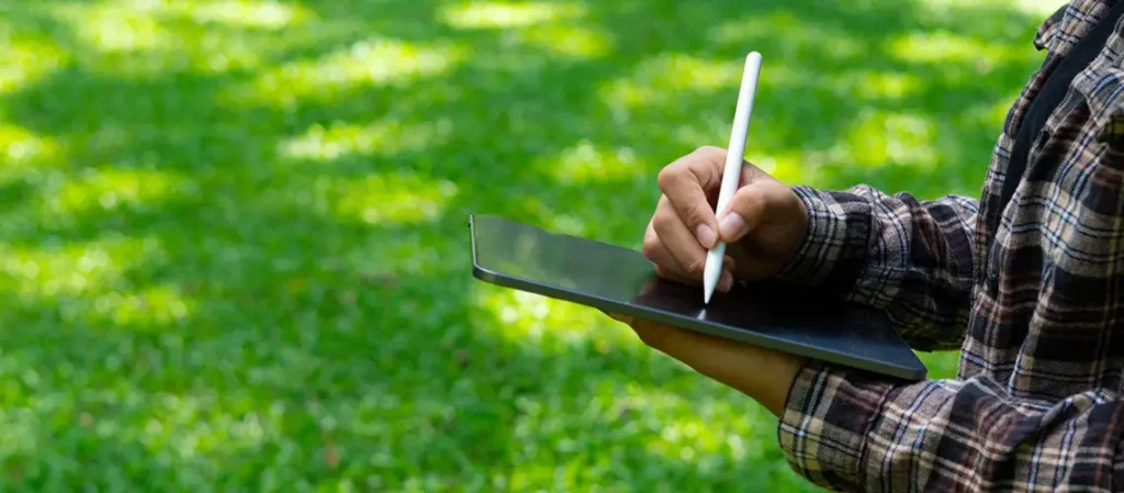 persona che utilizza un tablet camminando su un prato
